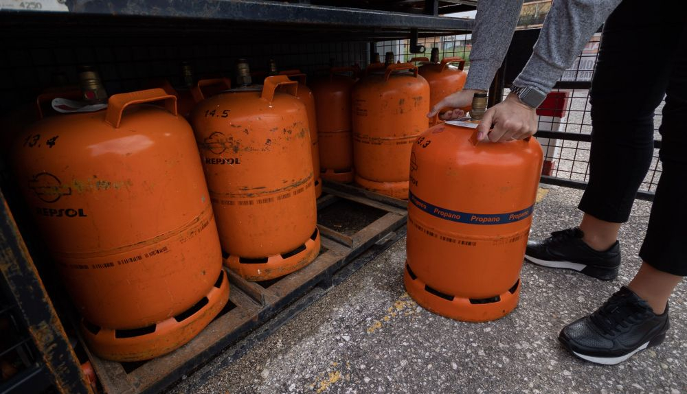 Una persona compra una bombona de butano en una gasolinera.